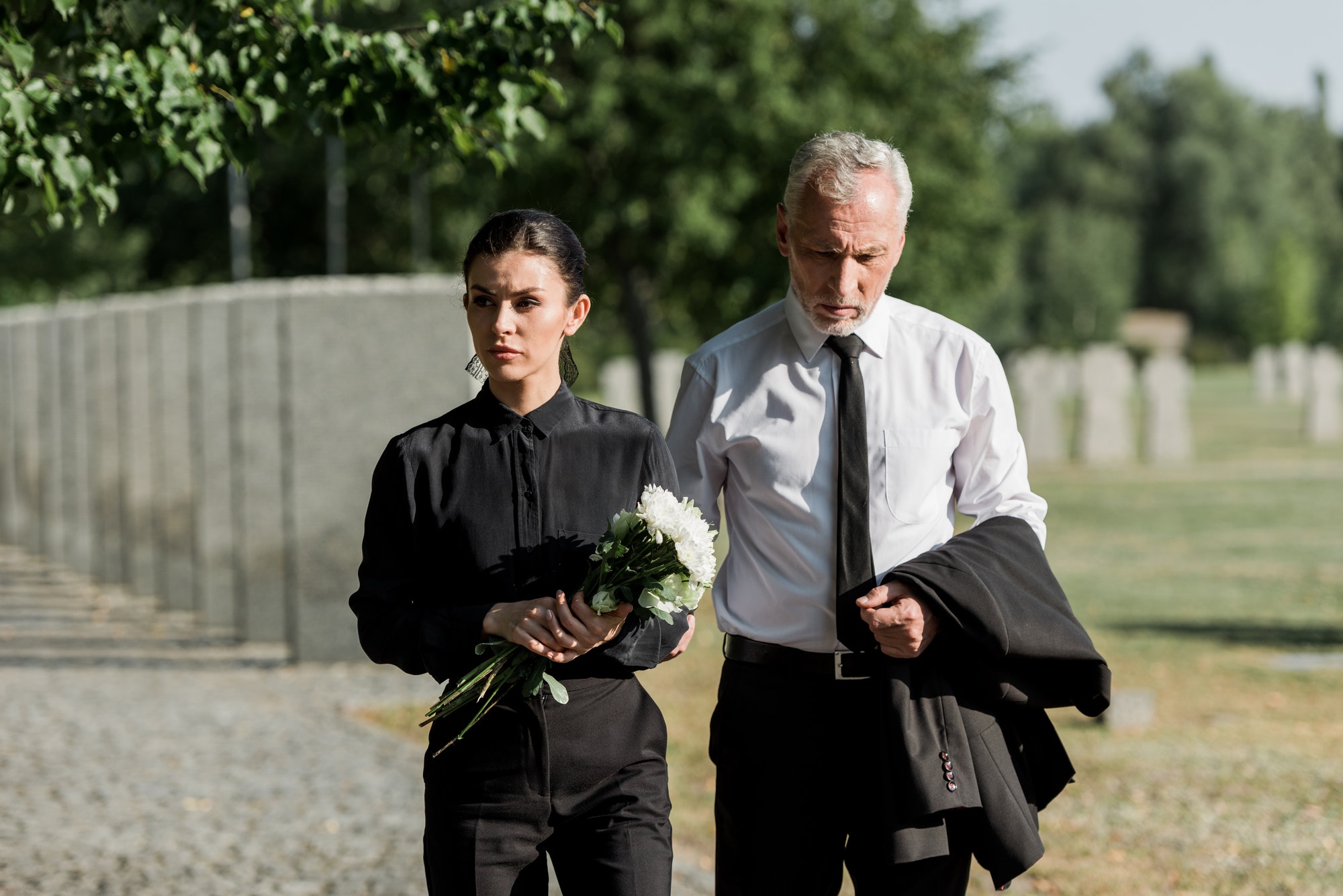 handsome-senior-man-standing-with-attractive-woman-holding-flowers-on-funeral.jpg